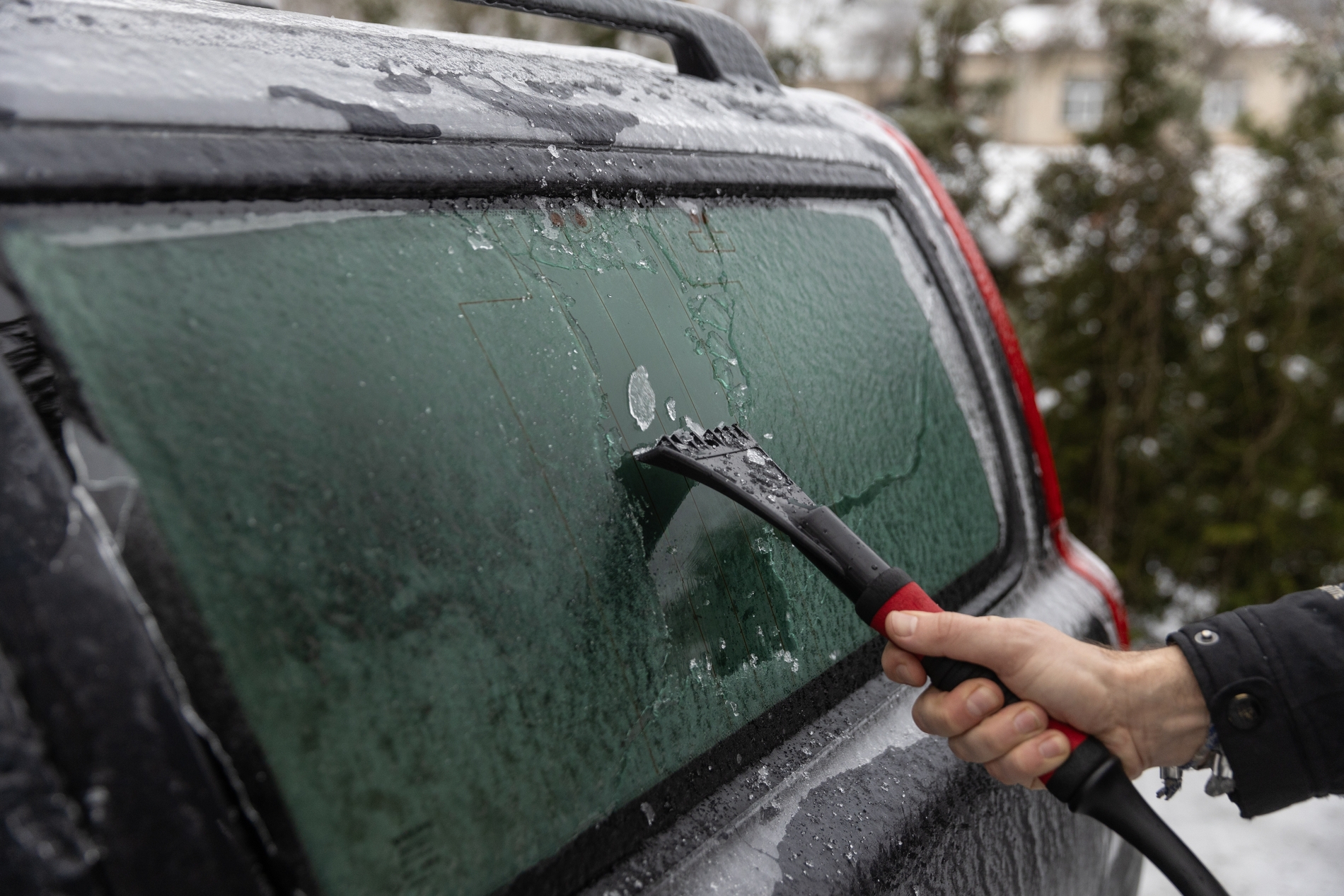 driver clearing all car windows ice snow before driving