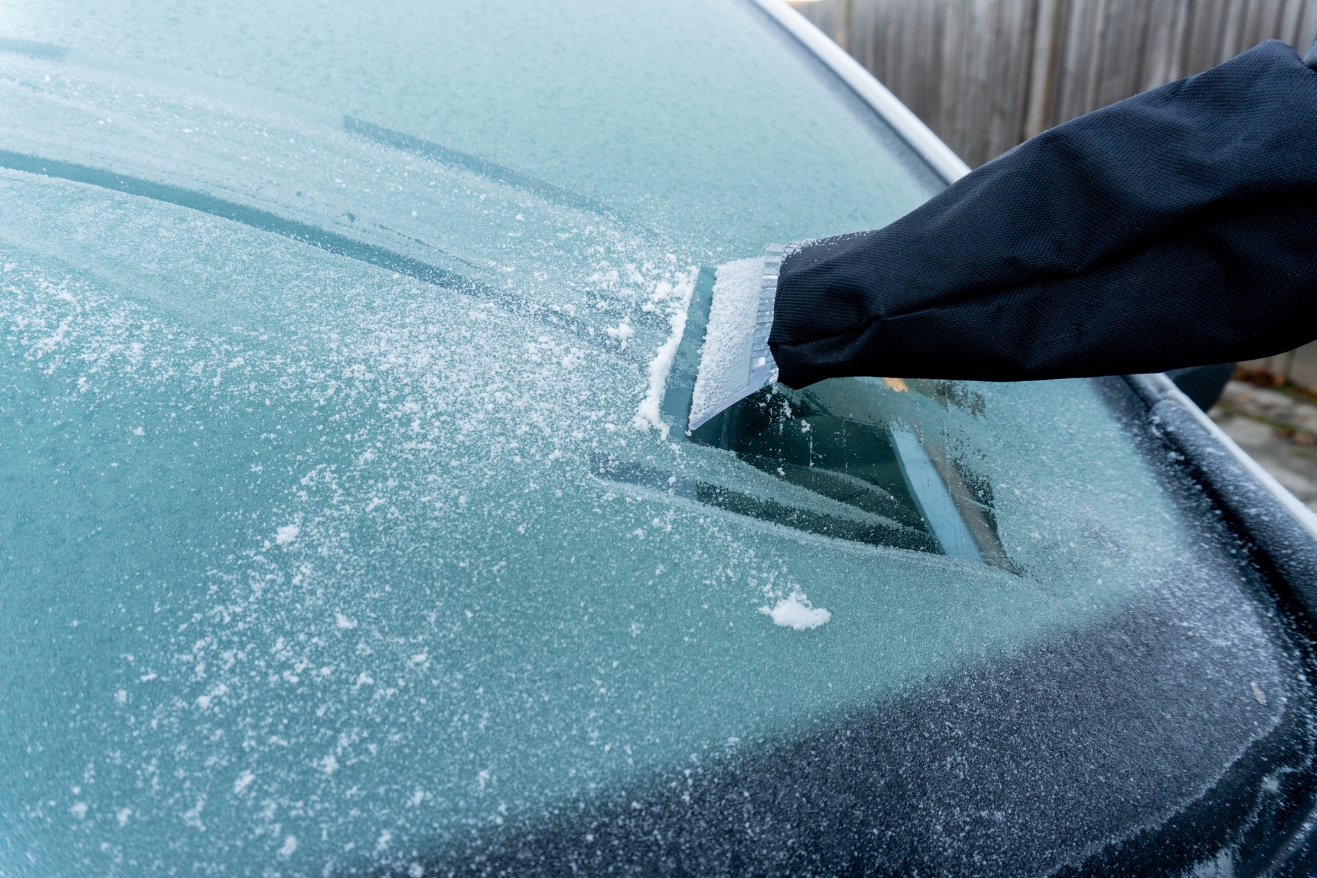 plastic ice scraper being used on car windshield close up